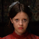 Mia Goth wears a red dress and has smeared eye make-up in Pearl.